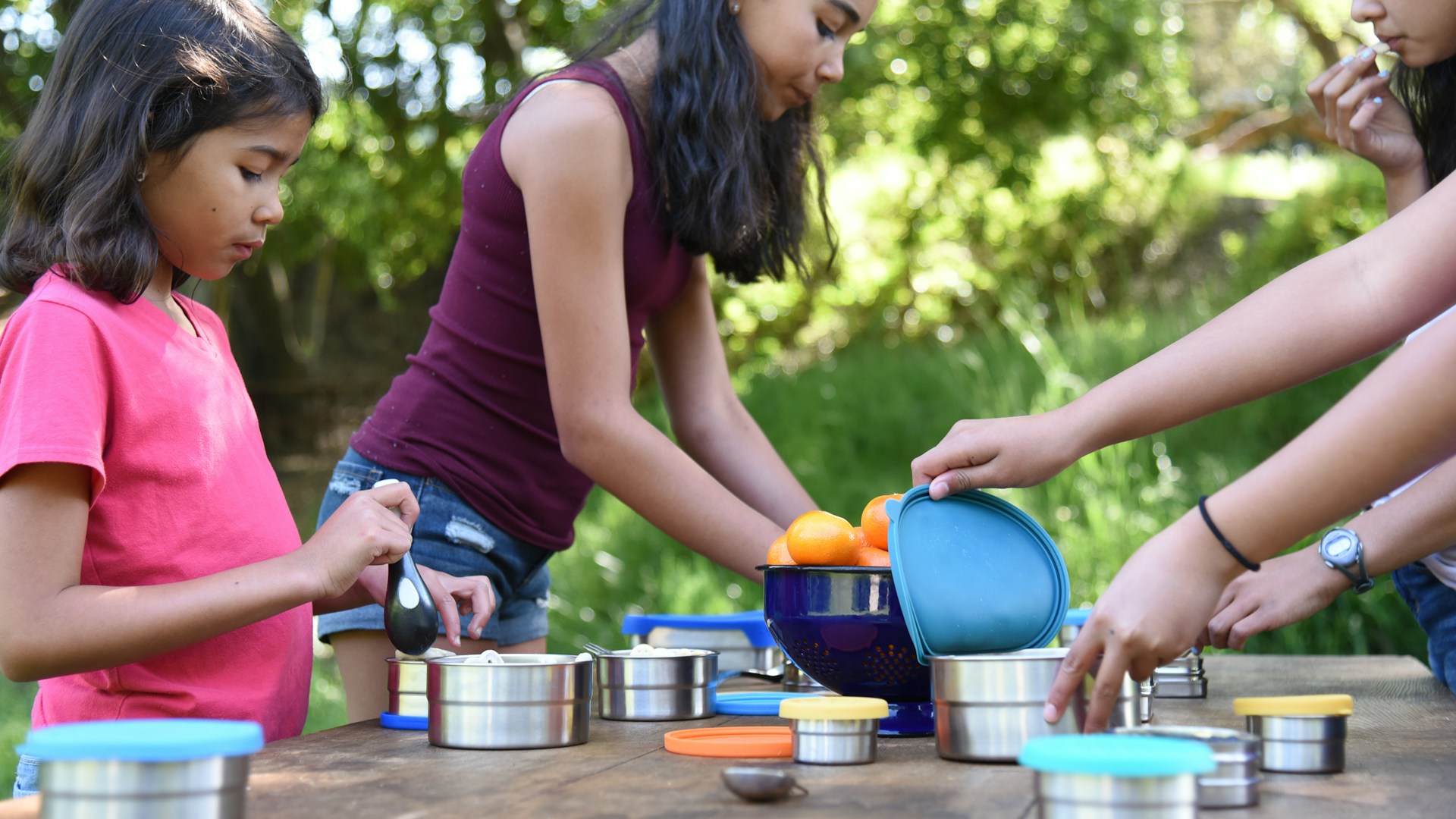 a group of people standing around a table with pots and pans